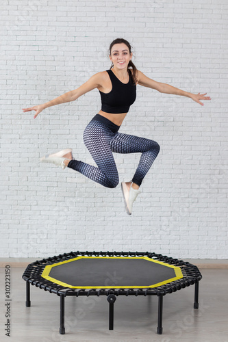 a young girl trains on a mini trampoline is engaged in fitness and stretching on a white  background
