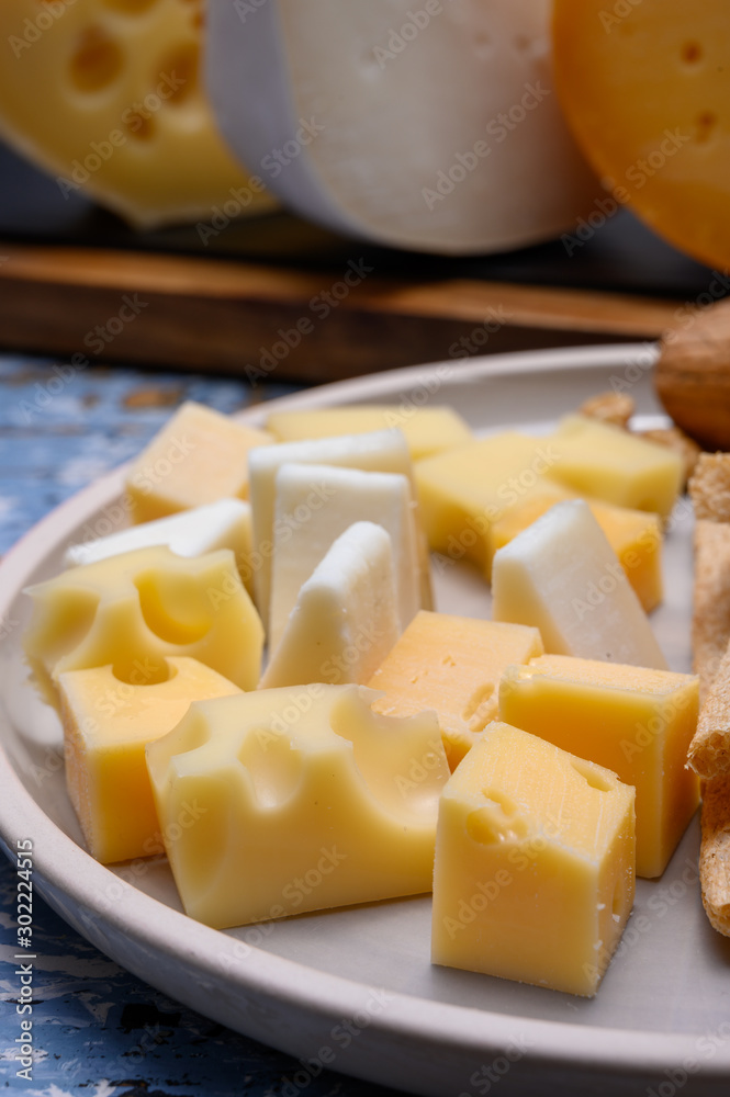 Tasty snacks, cheese blocks from Dutch yellow gouda and white goat hard cheeses and French holes cheese emmentaler Tasty snacks, cheese blocks from Dutch yellow gouda and white goat hard cheeses and French holes cheese emmentaler