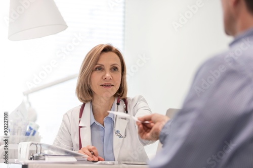 Doctor giving patient prescription in clinic