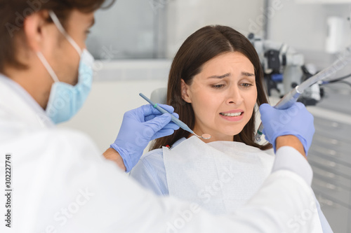 Frightened woman at dental office, looking panickly at dental tools