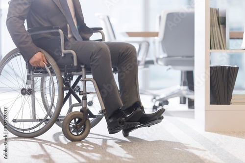 Businessman sitting on wheel chair in office