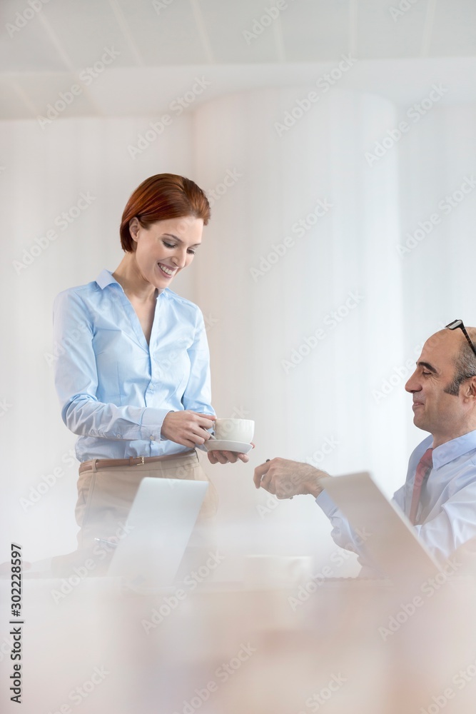Obraz premium Secretary giving coffee to businesman in office