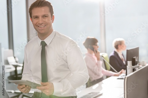 Businessman standing against colleagues working in office