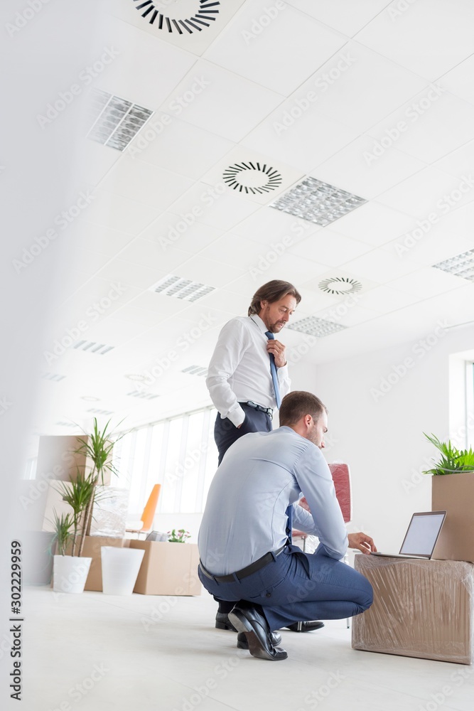 Businessman working against boxes in new office Businessman working against boxes in new office