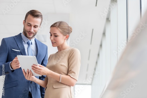 Bsinesswoman showing digital tablet to colleague in office