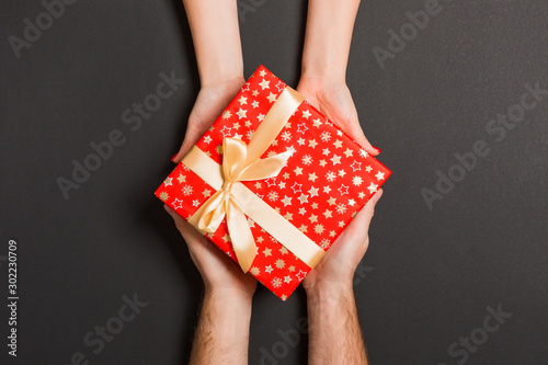Top view of two people sharing a present on colorful background. Holiday and surprise concept. Copy space © sosiukin