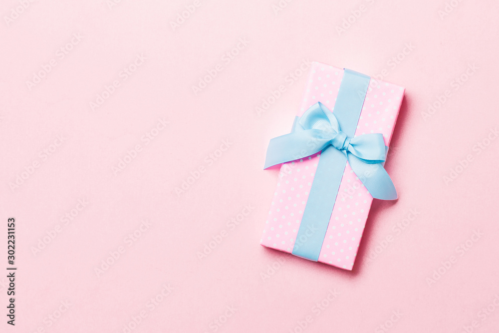 Top view Christmas present box with blue bow on pink background with copy space