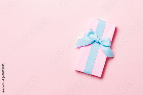 Top view Christmas present box with blue bow on pink background with copy space