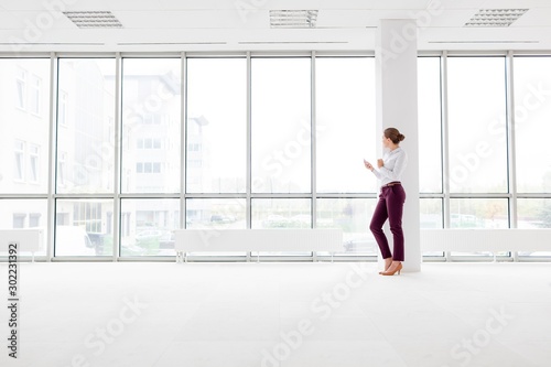 Young attractive businessowoman using smartphone in New office