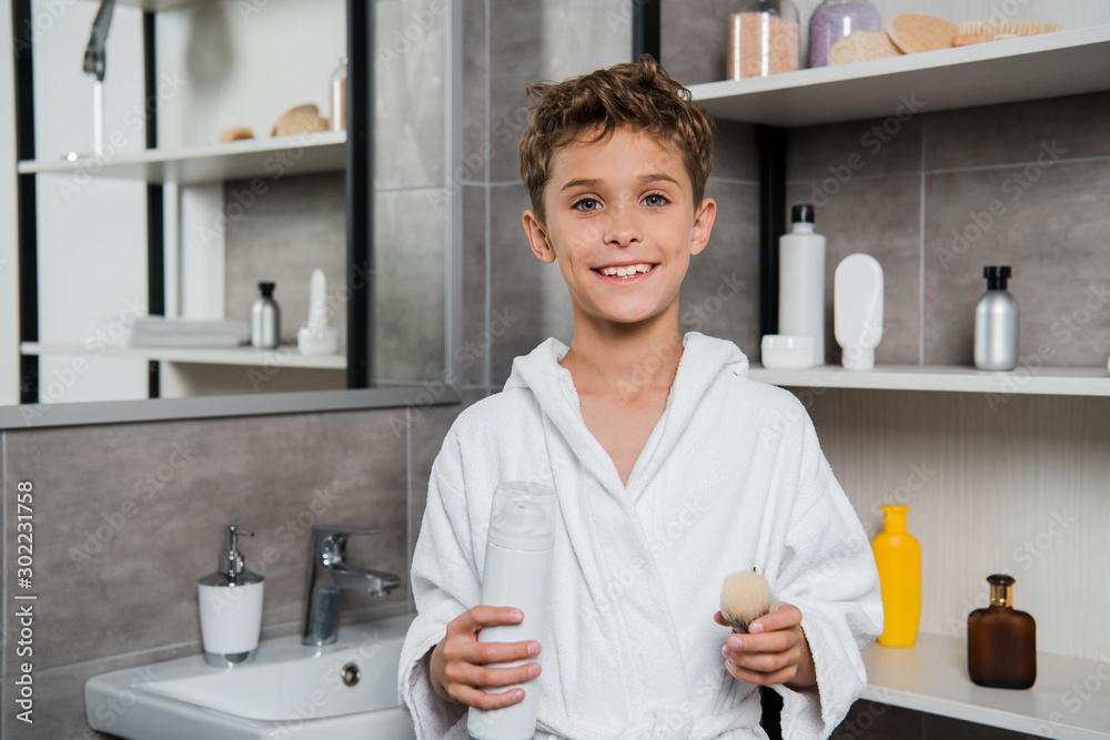 cheerful kid holding shaving brush and can with shaving foam cheerful kid holding shaving brush and can with shaving foam