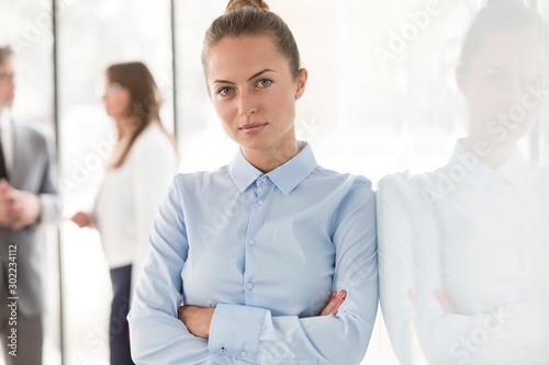 Young attractive businesswomen standing with arms crossed in office