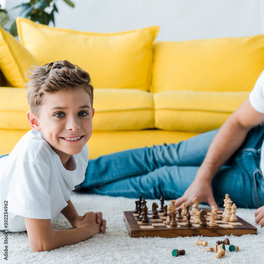 cropped view of father and son playing chess on carpet cropped view of father and son playing chess on carpet