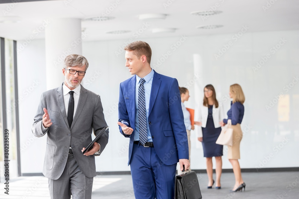 Businessmen discussing plans before meeting in office Businessmen discussing plans before meeting in office