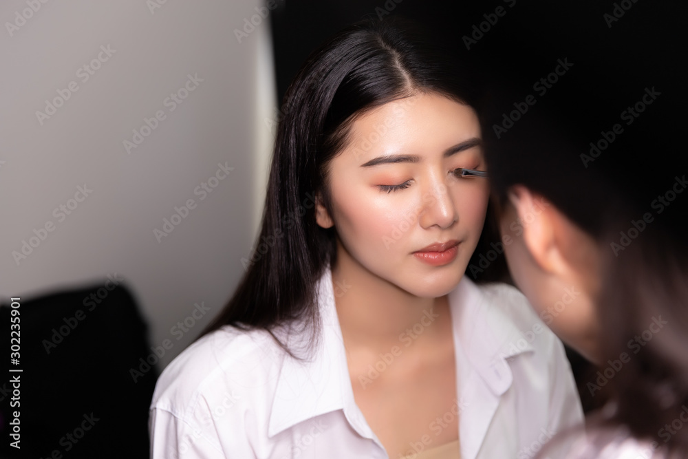Fototapeta premium Beautiful young asian woman and professional makeup artists applies eye shadow. Beautiful woman face. Perfect makeup.