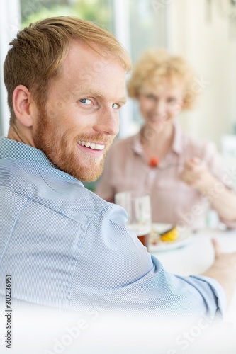 Portrait of smiling man sitting with woman in restaurant © moodboard