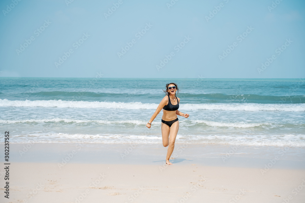 Happy young woman in sunglasses by the sea on a sandy beach, happiness and joy emotions, vacation freedom of travel Happy young woman in sunglasses by the sea on a sandy beach, happiness and joy emotions, vacation freedom of travel