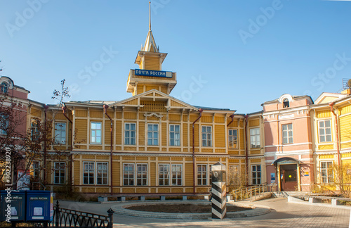 The building of the Central post office in Chita. Yellow building in the old style. On the square in front of the building is a pole with a zero mark.