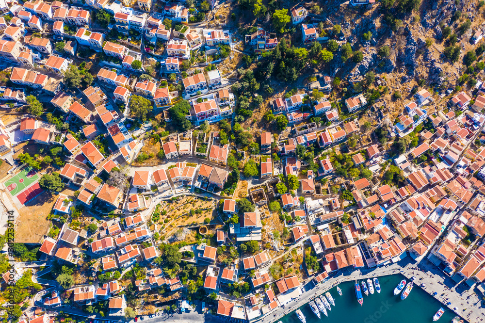 Aerial drone bird's eye view shot of scenic small town and Harbor with ships and yachts traditional Greek style white houses and the seaport with docked boats, island