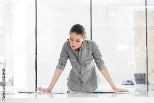 Businesswoman standing reading while analyzing documents in office