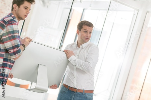 Businessmen moving computer in new office