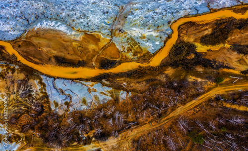 Fototapeta Naklejka Na Ścianę i Meble -  Aerial view drone flying forward over polluted river with destroyed ecosystem and copper tailing dump poisoning ground and water air emissions from industry environmental disaster in South Ural