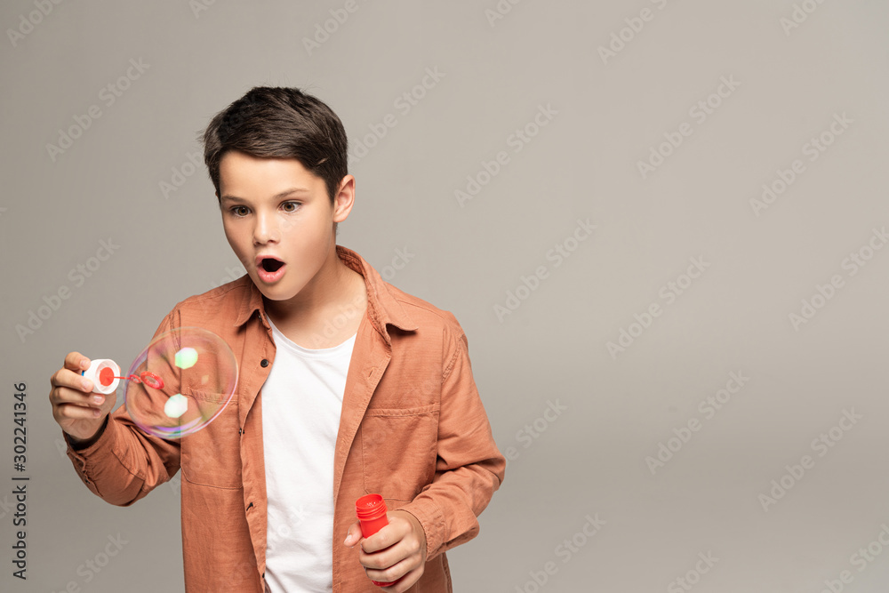 amazed boy looking at soap bubble isolated on grey amazed boy looking at soap bubble isolated on grey