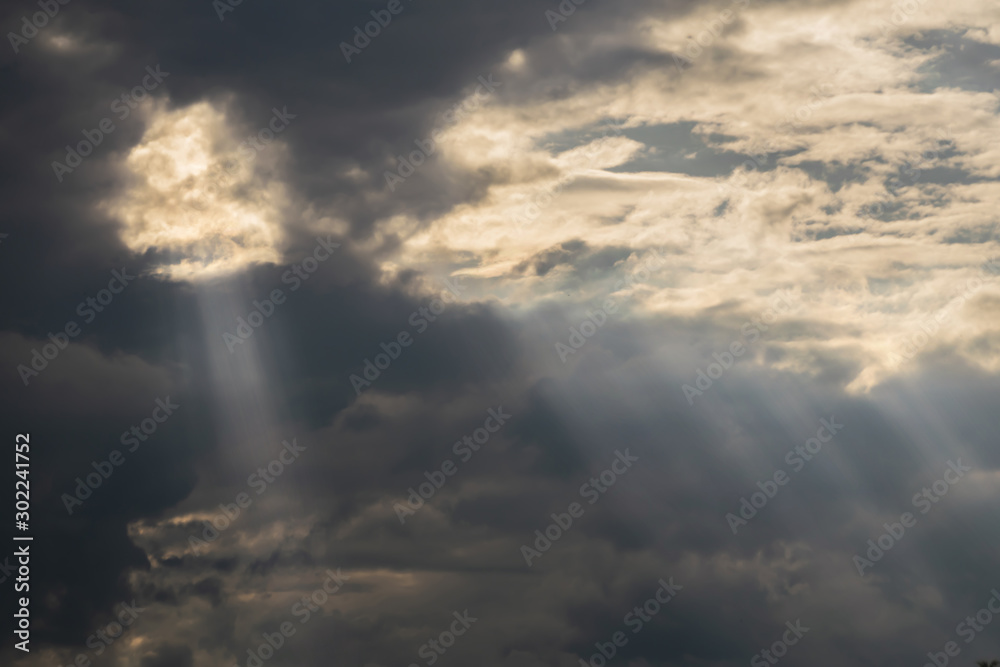 gray Cumulus clouds in a blue sky with rays of the sun
