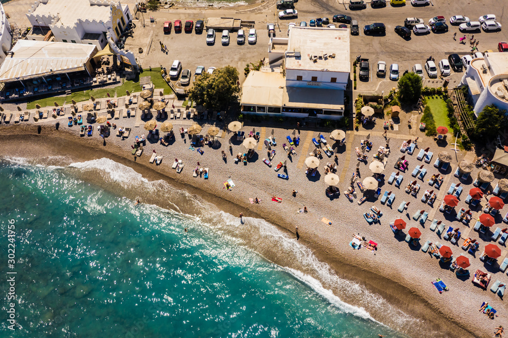 beach with umbrellas and sunbeds, resting people with clean water and beautiful stone bottom, top view,