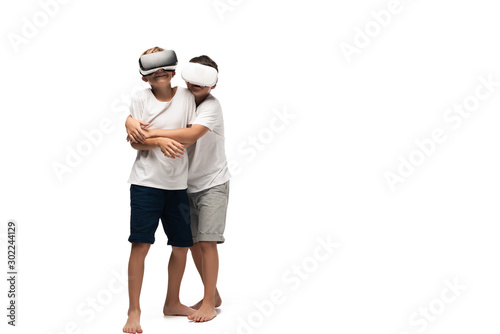 boy hugging smiling brother while using vr headsets together on white background
