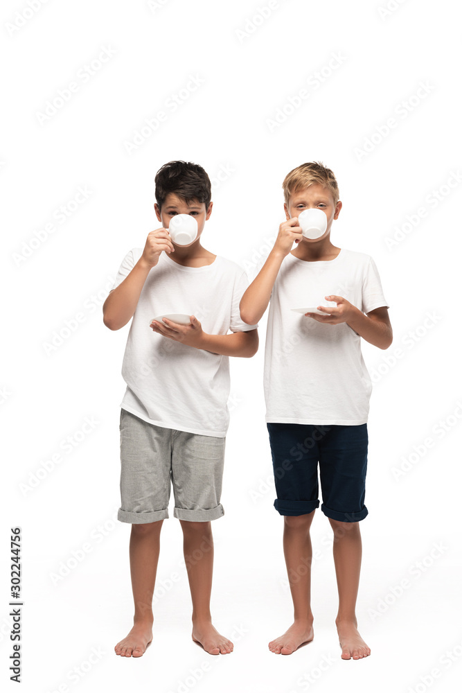 two brothers looking at camera while drinking coffee on white background two brothers looking at camera while drinking coffee on white background