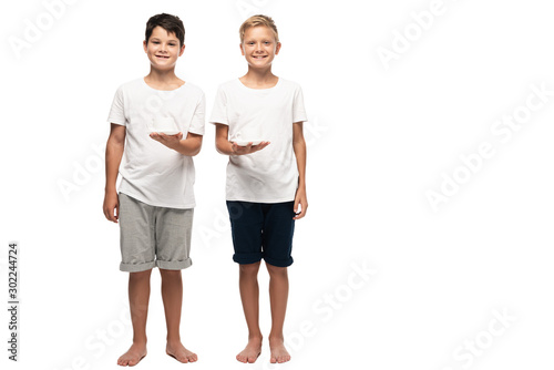 two smiling brothers looking at camera while holding coffee cups on white background photo