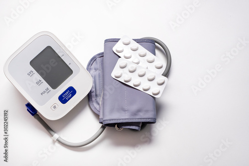 Hypertension, medical care medication pills. Medicines and blood pressure monitor on a white table and blue wall. Medicine and healthy lifestyle,