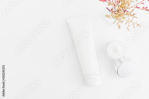 White serum bottle and cream jar, mockup of beauty product brand. Top view on the white background.