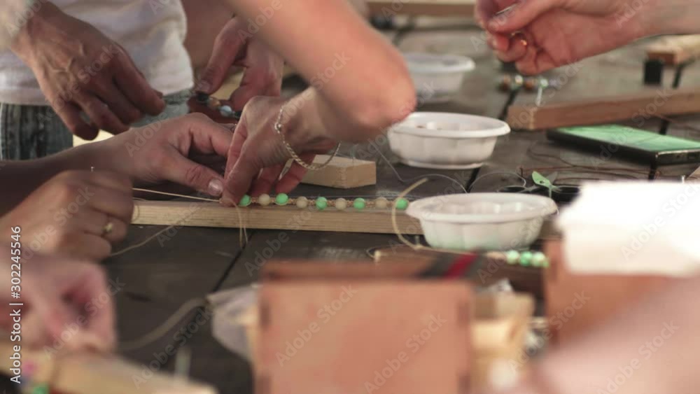 Close-up of female hands stringing beads on a thread, making a jewelry bracelet Close-up of female hands stringing beads on a thread, making a jewelry bracelet
