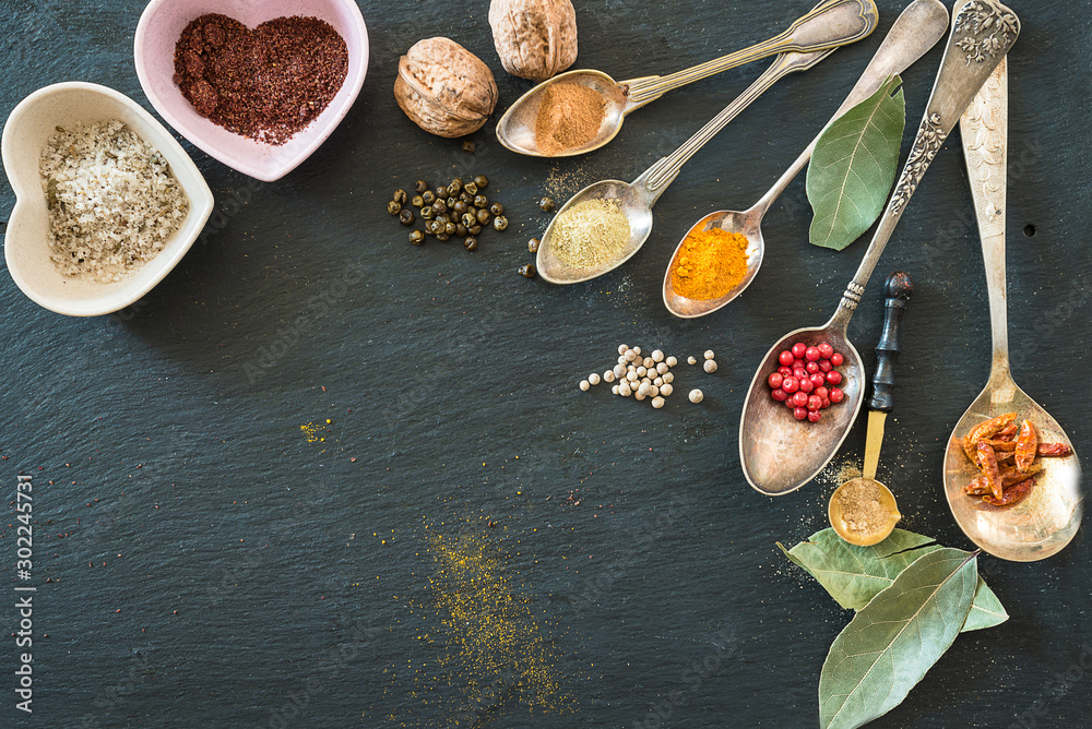 Background with Various of spices in the vintage spoons on the black slate. Copy space, flat lay, selective focus