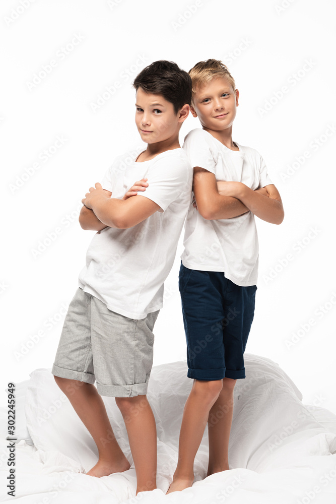 two cunning boys standing back to back with crossed arms and smiling at camera isolated on white two cunning boys standing back to back with crossed arms and smiling at camera isolated on white