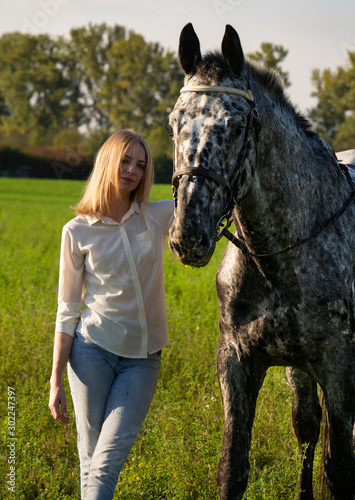 Beautiful young woman with a horse, on a green summer meadow. © alex_marina