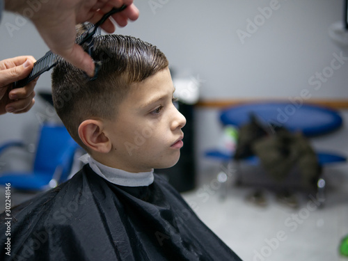 cute young boy having a haircut at a hairderesser