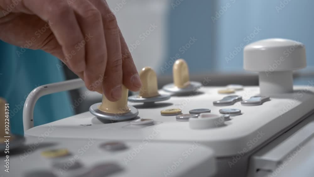 Surgeon operates robotic diagnostic system via remote control panel, hospital, operating roon, hands close-up Surgeon operates robotic diagnostic system via remote control panel, hospital, operating roon, hands close-up