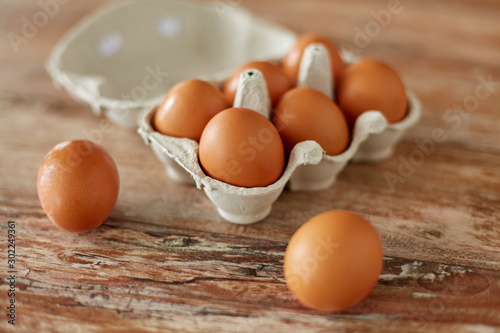 food, culinary and cooking concept - close up of natural chicken eggs in cardboard box on wooden table