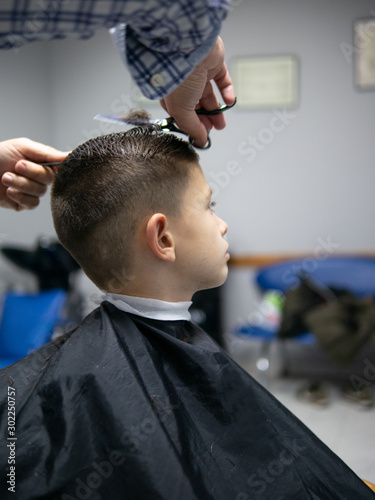 cute young boy at the hairdresser having a haircut