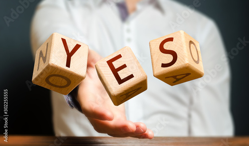 A man throws cubes with letters and makes up the word YES. Agreement and acceptance, answer the question. Courage and irresistibility, zeal forwards, consent. Confirmation and acceptance, approval photo