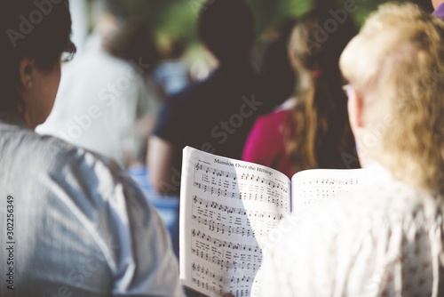 Foto Selective focus shot from behind of people reading notes in the choir with a blu