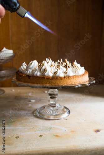 Lemon tart with french meringue caramelized on top, on a rustic table, french meringue caramelized with a food torch. photo