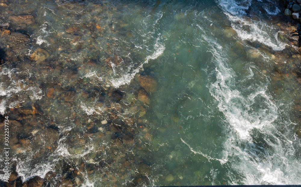 top view of a rocky channel and almost clear bluish-muddy water of a mountain river top view of a rocky channel and almost clear bluish-muddy water of a mountain river