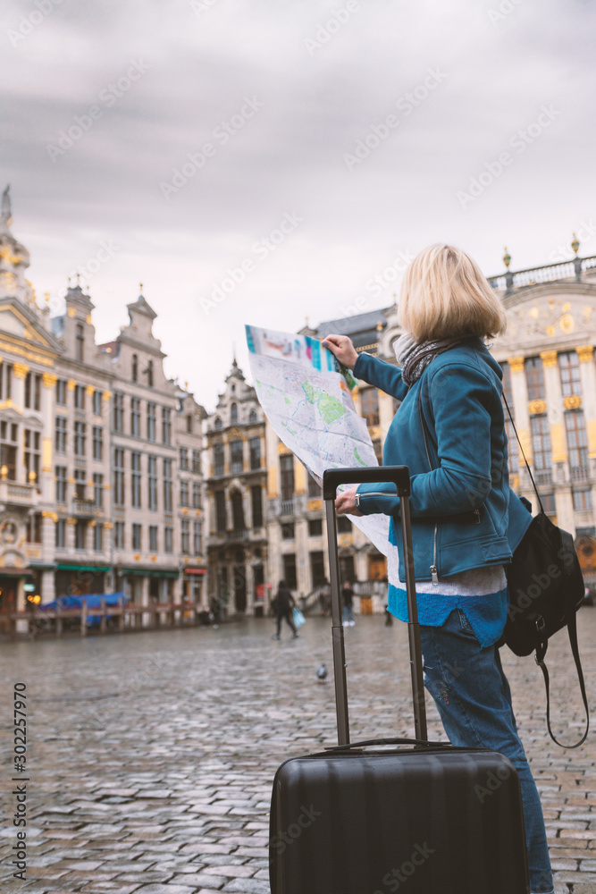 Woman tourist goes with a suitcase at the Grand Place in Brussels, Belgium