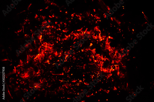 The burning coals of a bonfire at night. Abstract background of flickering embers. Closeup