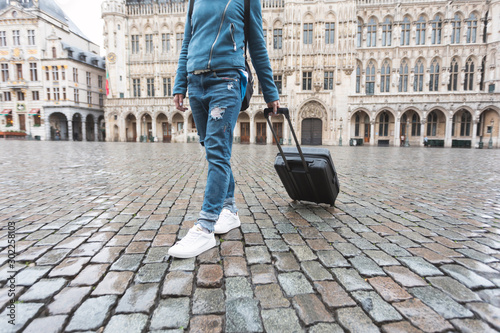 Woman tourist goes with a suitcase at the Grand Place in Brussels, Belgium