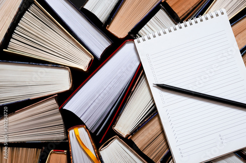 Lots of colourful thick open books stand on a dark background
