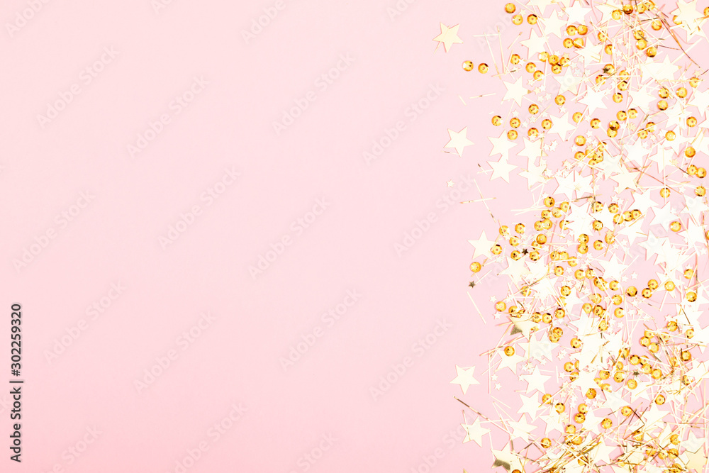 Christmas modern composition. Golden decorations, confetti, stars on pastel pink background. Christmas, New Year, winter concept. Flat lay, top view, copy space